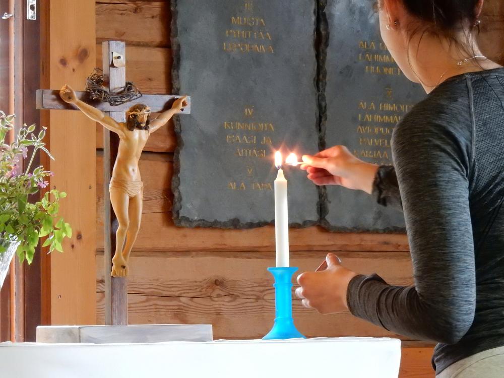 Nainen sytyttää kynttilän alttarille.