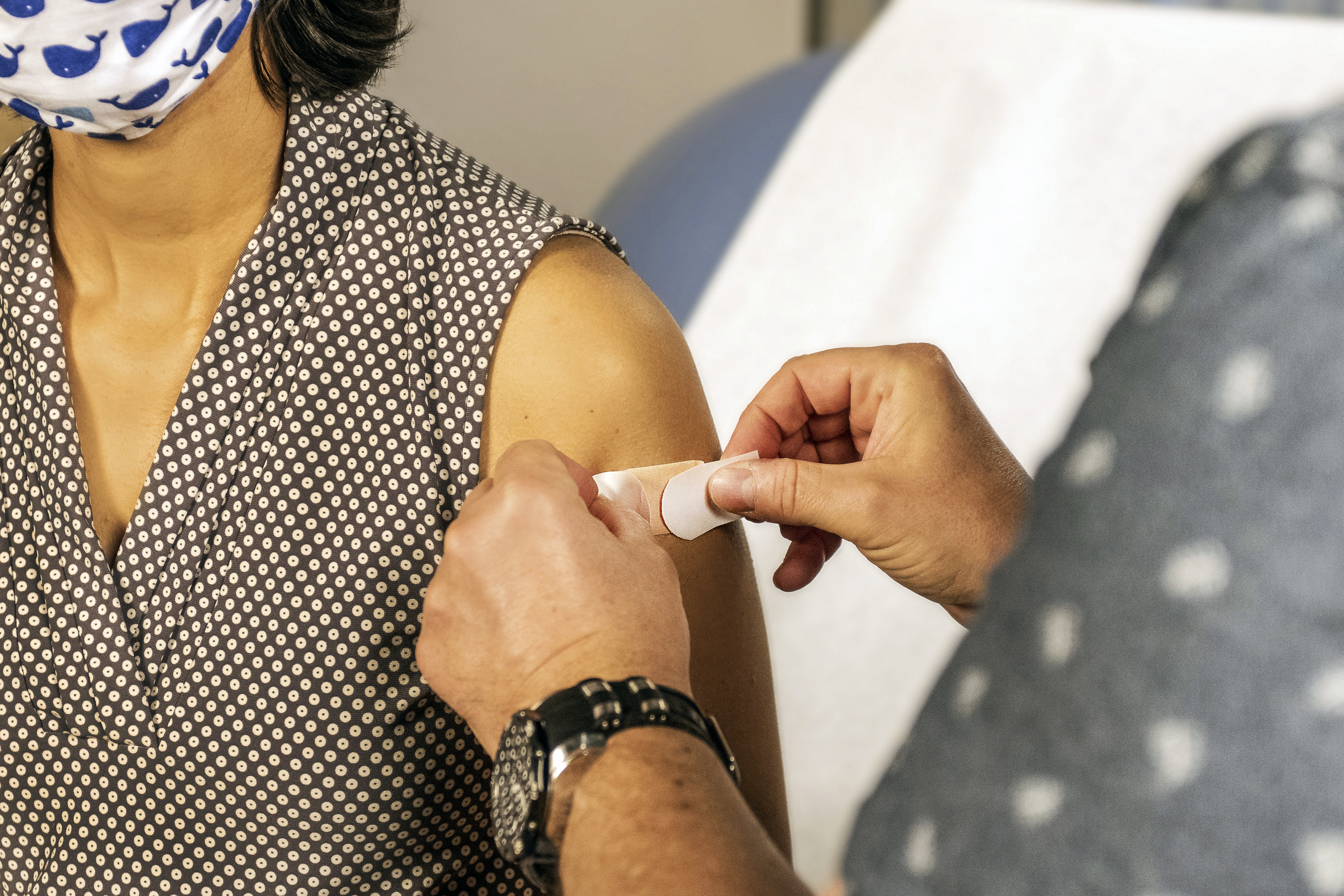 Naisen käsivarteen laitetaan laastari rokotuksen jälkeen.